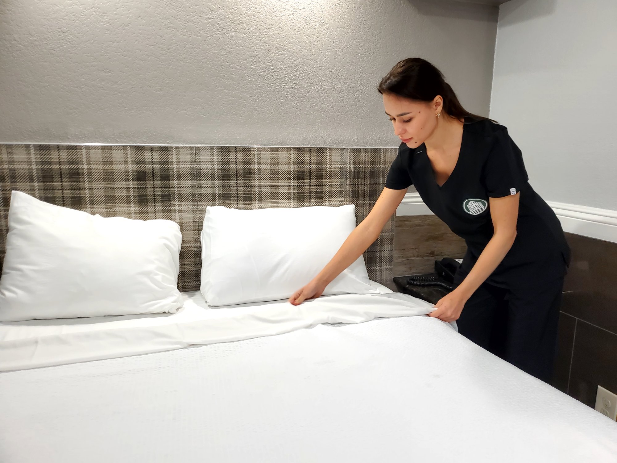 AmeriCorp room attendant making a hotel bed in Los Angeles